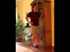 a man standing in front of a tall wooden grandfather's cupboard with his hands on the door handle