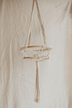 a white piece of cloth hanging from a rope on a wall with a knot at the end