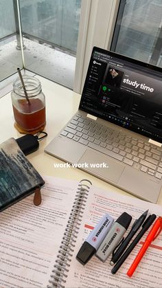 an open notebook sitting on top of a desk next to a laptop computer and pen