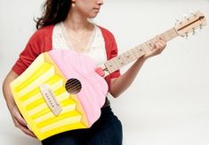 a woman is holding a pink and yellow ukulele with an accordion on it