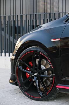 a black sports car with red rims parked on the street