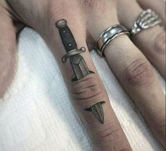 a person with a knife tattoo on their left hand and another one in the background