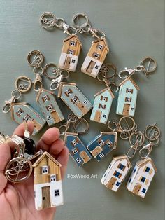 a hand holding a house shaped keychain in front of a bunch of small houses