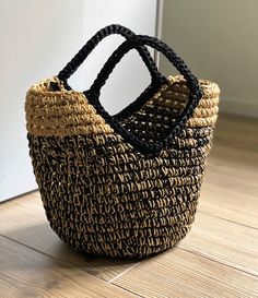 a black and brown basket sitting on top of a wooden floor next to a door