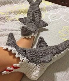 two crocheted shark shoes laying on top of a bed