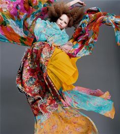 a woman in a colorful dress is dancing with her arms spread out to the side