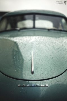 the front end of an old car with rain drops on it