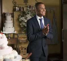 a man in a suit standing next to a cake