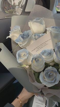 a bouquet of white roses sitting in the back seat of a car with a note attached to it