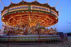 the merry go round is lit up at night with lights on it's sides