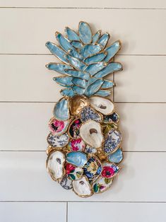 a pineapple shaped wall hanging on the side of a white wooden wall with blue and pink flowers