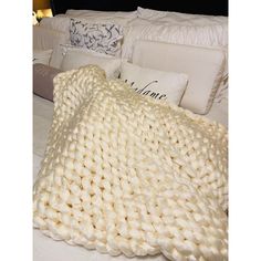 a white blanket on top of a bed next to pillows