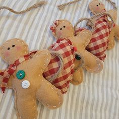 three brown teddy bears with red and white checkered fabric on a striped bed sheet