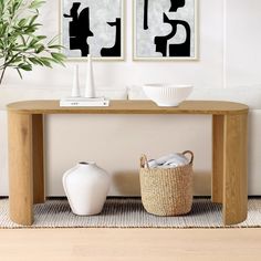 two black and white abstract paintings hang on the wall above a wooden table in a living room