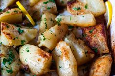 a white bowl filled with potatoes and lemon wedges