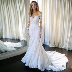 a woman in a white wedding dress standing next to a mirror