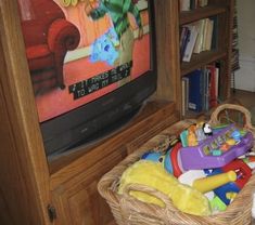 a basket full of toys sitting in front of a television