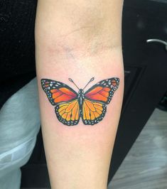 an orange butterfly tattoo on the arm