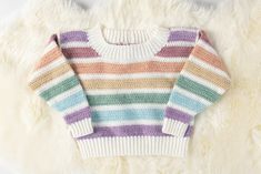 a multicolored striped sweater laying on top of a white furnishing area