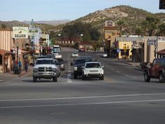 cars are driving down the street in front of shops and businesses on a sunny day