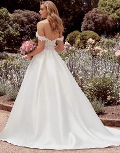 a woman in a white wedding dress standing on some steps looking at the flowers and bushes