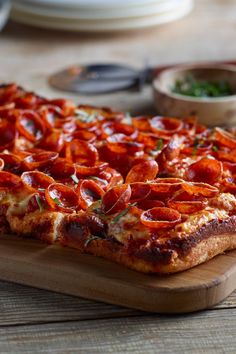 a pizza with pepperoni on it sitting on a cutting board