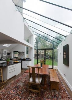 a dining room table sitting under a skylight next to a kitchen area with an open floor plan