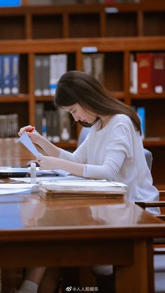 a woman sitting at a table with a book in her hands