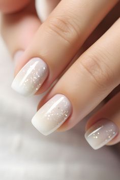 a woman's hand with white and gold nail polishes on her nails,