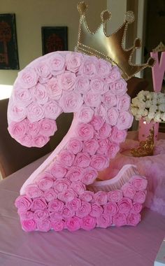a large number made out of pink roses on top of a table with a crown