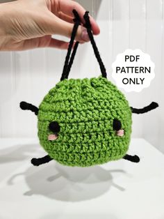 a green crocheted bag hanging from a hook with the words pattern only above it