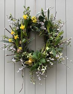 a wreath hanging on the side of a wall with flowers and greenery around it