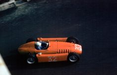 an orange race car driving down the street