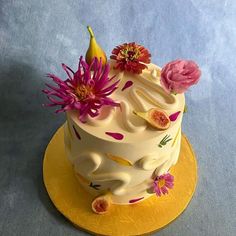 a white cake with flowers and fruit on top is sitting on a yellow platter