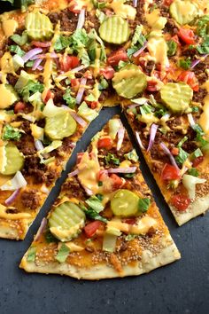 a pizza with several different toppings cut into slices and placed on a black surface