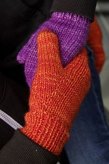 a pair of purple and orange mittens sitting on top of a persons lap,