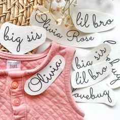 pink shirt with white letters on it next to flowers and wicker basket filled with leaves