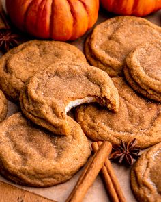 several cookies and cinnamon sticks on a wooden surface with pumpkins in the back ground