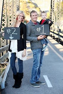 a man and woman standing on a bridge with a sign that says i love you