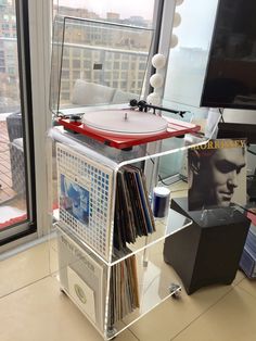 a record player sitting on top of a shelf in front of a window next to a tv