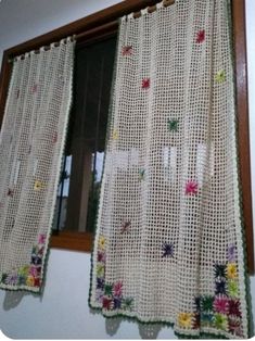 a curtain with flowers on it hanging from a window sill in front of a mirror