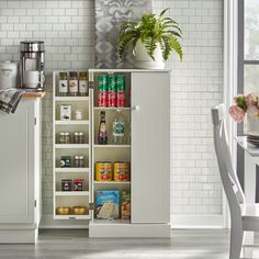 an open cabinet in the kitchen with food and drinks on it, next to a dining room table