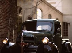 an old truck is parked on the side of the road in front of a brick building