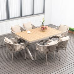 a table and chairs on a deck with flowers in the center, next to a potted plant