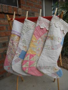 three quilted stockings hanging on clothesline next to brick wall and potted plant