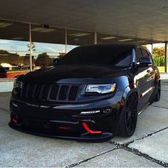 a black jeep is parked in front of a building with its hood up and lights on