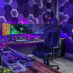 a computer desk with two monitors and a keyboard on it in front of purple hexagon tiles