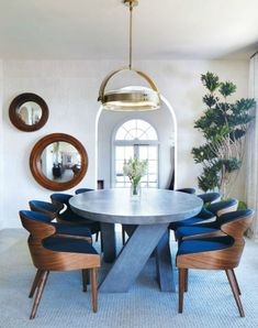 a dining room table with blue chairs and a round light fixture hanging over it's head