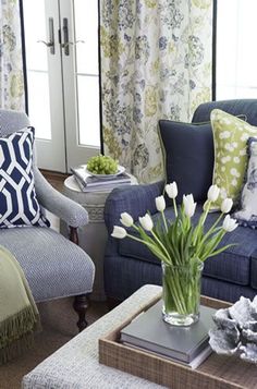 a living room with blue couches and white flowers in a vase on the coffee table