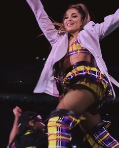 a woman is dancing on stage with her arms in the air